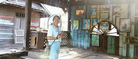 A rustic wooden building with a corrugated metal roof, a wooden door, and a wall adorned with framed pictures.
