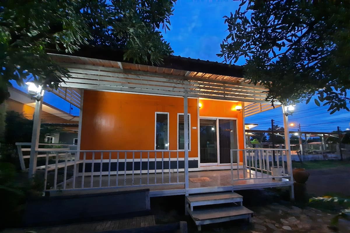 A small, orange building with a covered porch and steps leading up to the entrance.