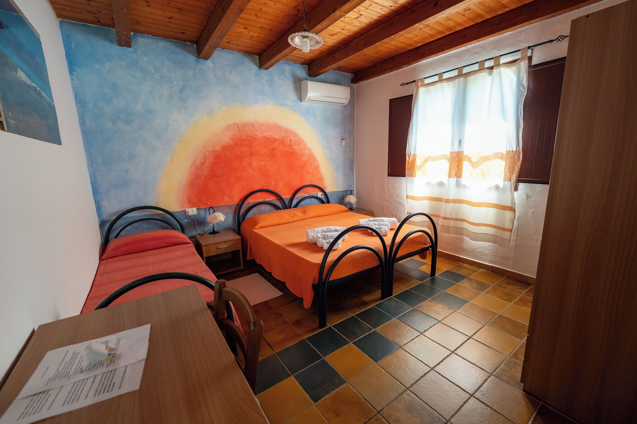 A room with a bed, a small table, a chair, and a window with curtains.