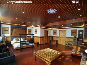 A traditional room with a bed, wooden furniture, and a ceiling with wooden beams and recessed lighting.