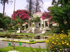 Un jardín con una fuente, un pabellón y un estanque.