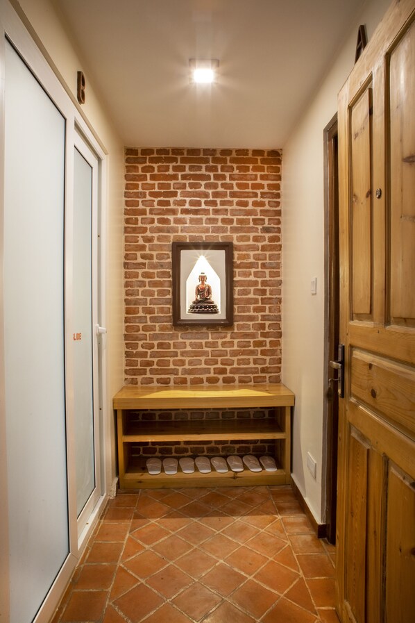 Un pasillo con pared de ladrillo, un cuadro enmarcado, un banco de madera y una puerta.