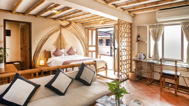 A room with a bed, a sofa, a dining table, and a window with curtains.