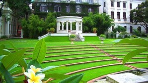 A formal garden with a central pavilion, well-manicured lawns, and classical architecture.