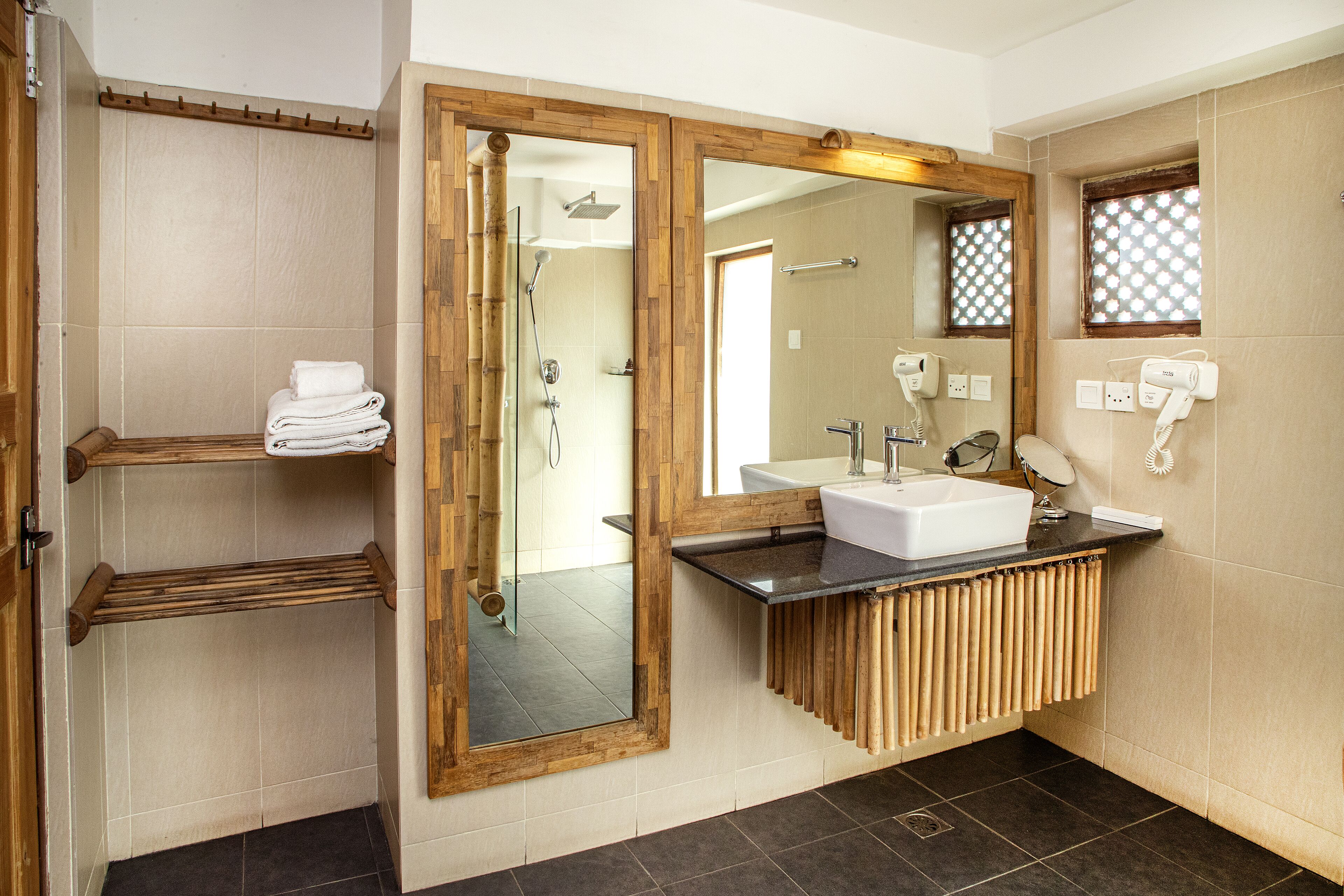 A bathroom with a wooden vanity, a large mirror, a shower, and a towel rack.