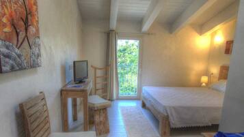 Una camera da letto con un letto, una scrivania con un computer, una sedia e vista sull'esterno.