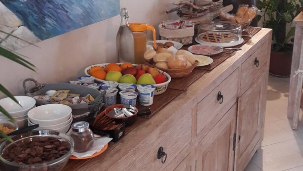 A wooden buffet table with various food items and a painting of boats on the wall. - La Casa di Pier (Olbia)