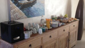 A wooden buffet with various dishes and a painting of a harbor scene on the wall. - La Casa di Pier (Olbia)