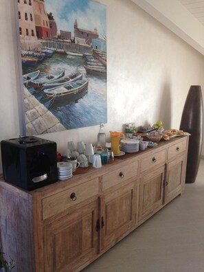 A wooden buffet with various dishes and a painting of a harbor scene on the wall. - La Casa di Pier (Olbia)