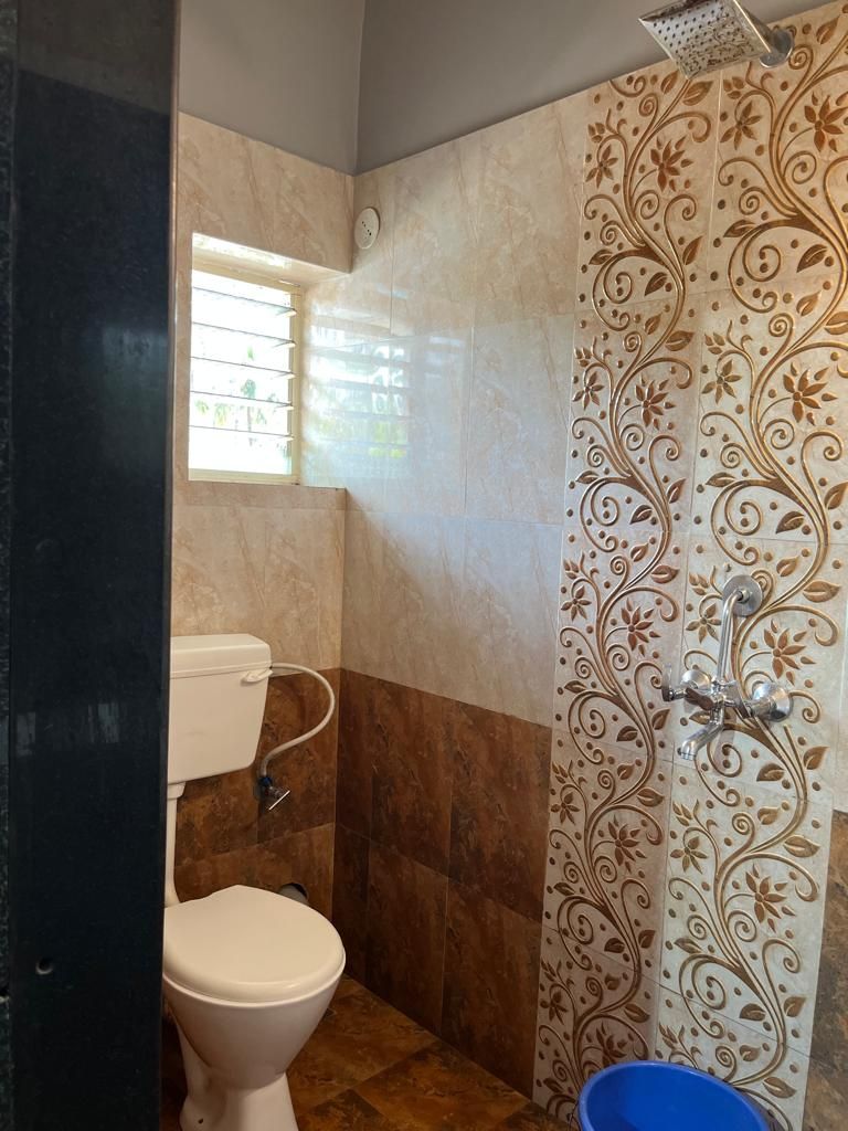 Une salle de bain équipée de toilettes, d’une douche et de carreaux décoratifs sur les murs.