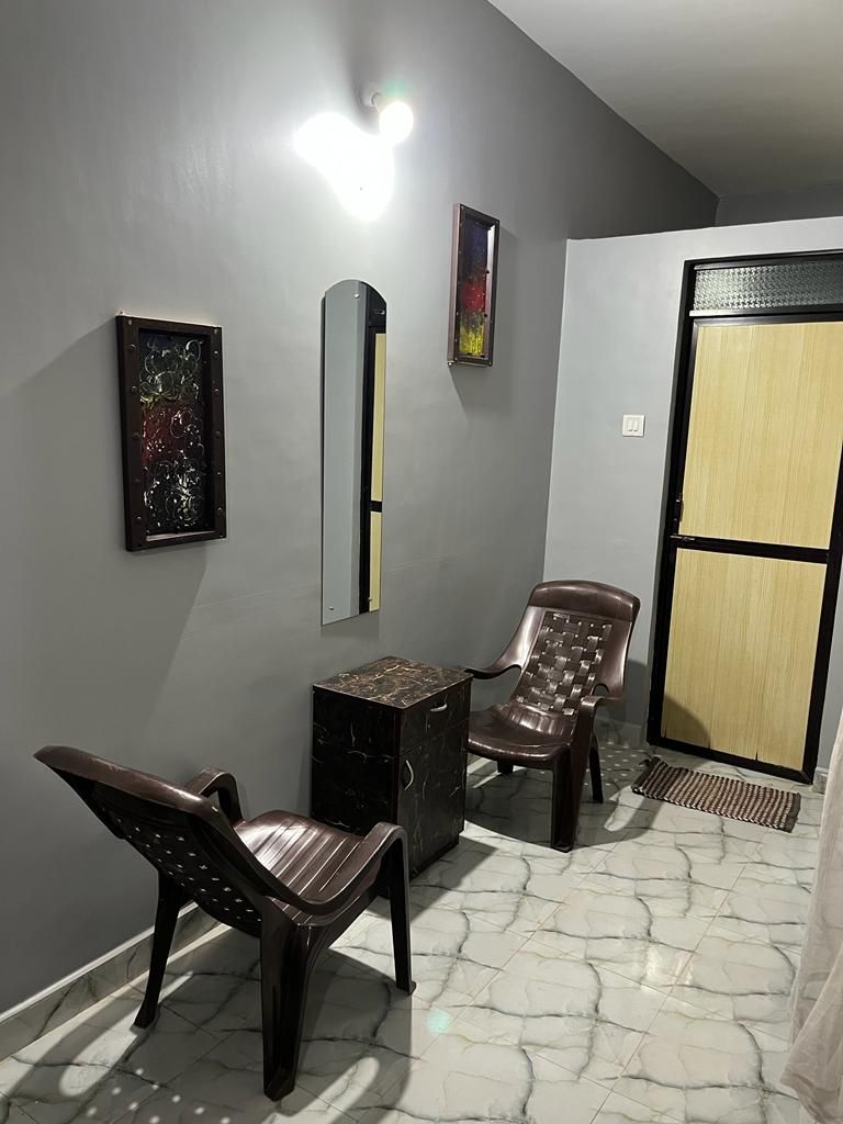 Une pièce avec un sol en marbre, un fauteuil marron, une petite table et une porte dotée d’un cadre noir.