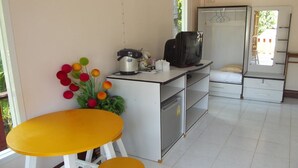 Eine kompakte Küche mit Essbereich, einem kleinen Kühlschrank, einer Mikrowelle und einer Kaffeemaschine.