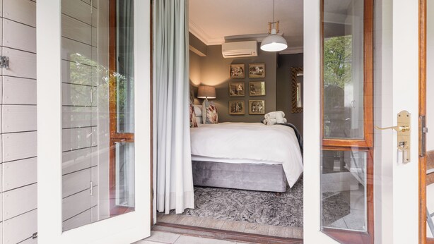 A bedroom with a bed, a window with curtains, a ceiling light, and framed pictures on the wall. - Avemore Jan Cats No 2 (Stellenbosch)