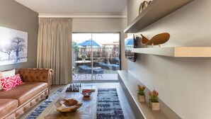A modern living room with a leather sofa, a coffee table, and a view of the outdoor patio.