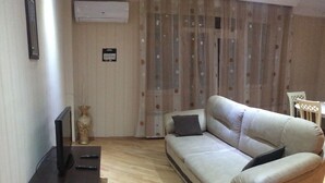 A living room with a sofa, a TV stand, and a curtain. - Bachos Apartment (Tbilisi)