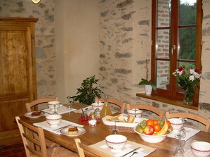 Enjoy meals in this charming dining area with a wooden table, surrounded by a fruit bowl and a potted plant.