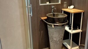 A bathroom with a glass shower enclosure, a sink with a stone basin, and a mirror above it. - Hotel Le Saint Amant (Le Palais)