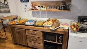 A breakfast buffet with various food items, a coffee machine, and a microwave. - Hotel Le Saint Amant (Le Palais)