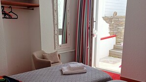A hotel room with two beds, a chair, a mirror, and a window with curtains. - Hotel Le Saint Amant (Le Palais)