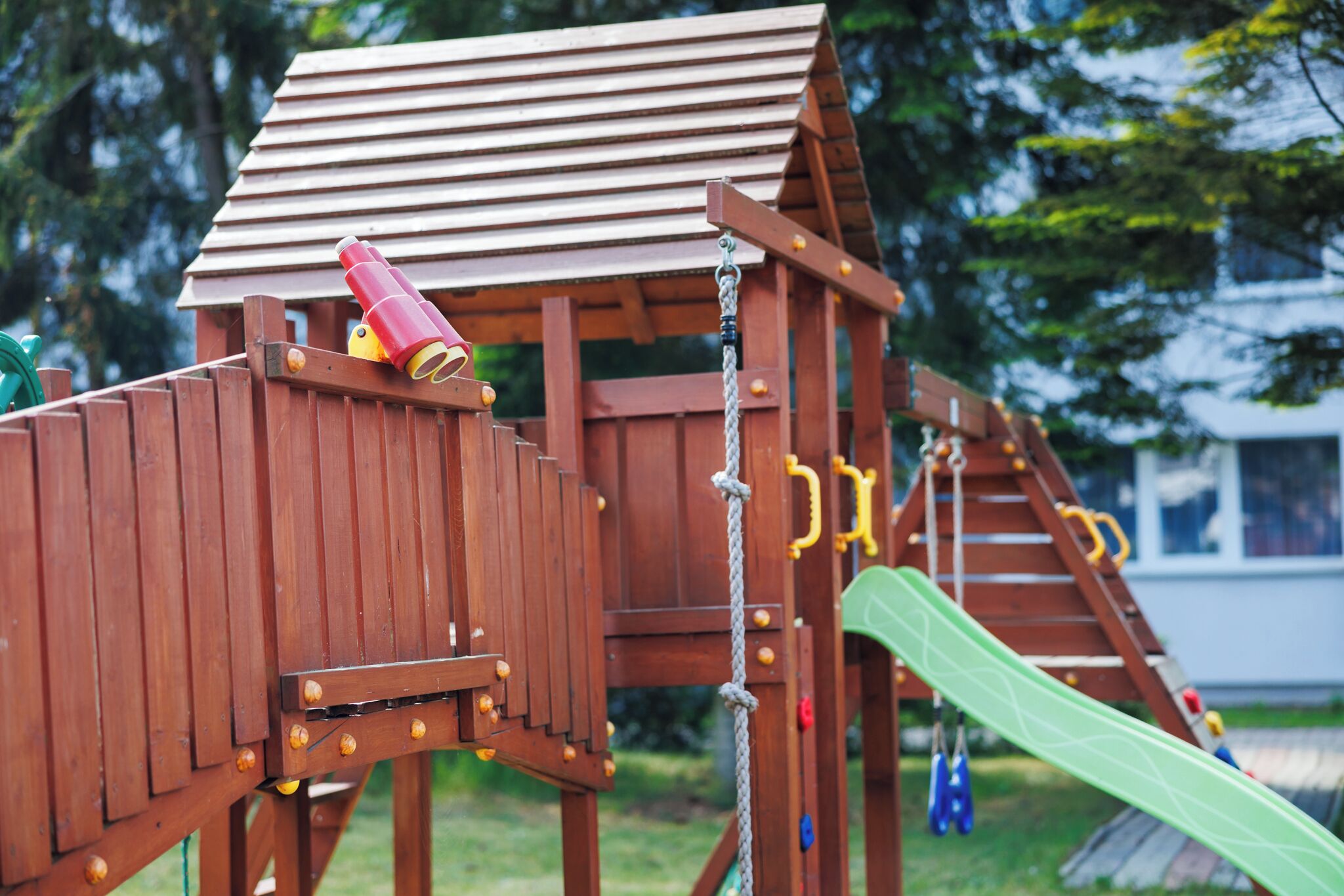 A wooden play structure with a slide and climbing elements.