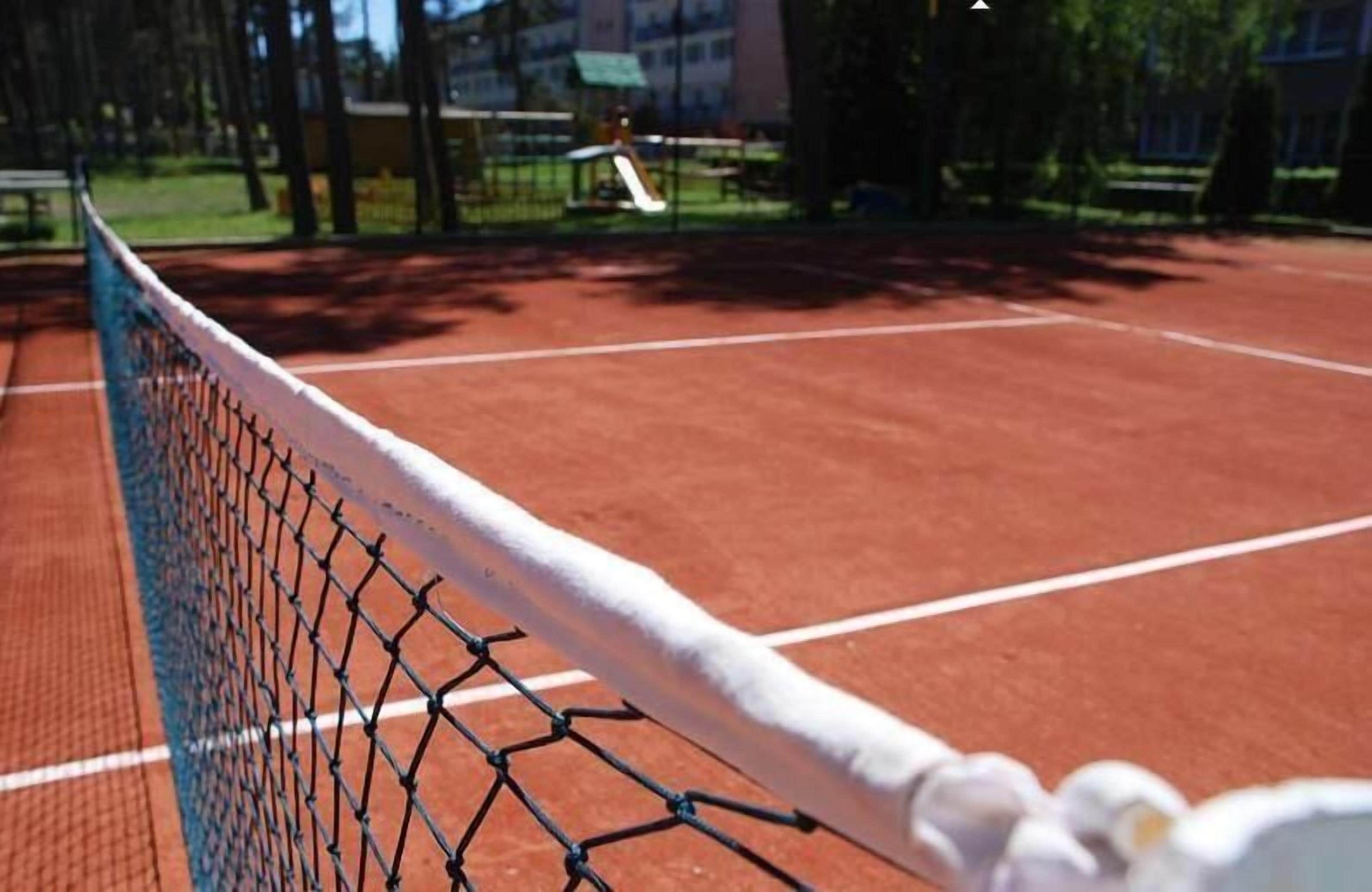 A tennis court with a net and a fence.