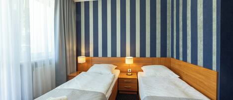 A hotel room with two beds, a wooden headboard, and a striped wall.
