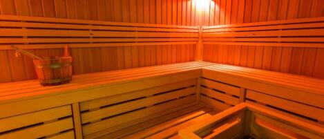 A sauna with wooden benches and a bucket.