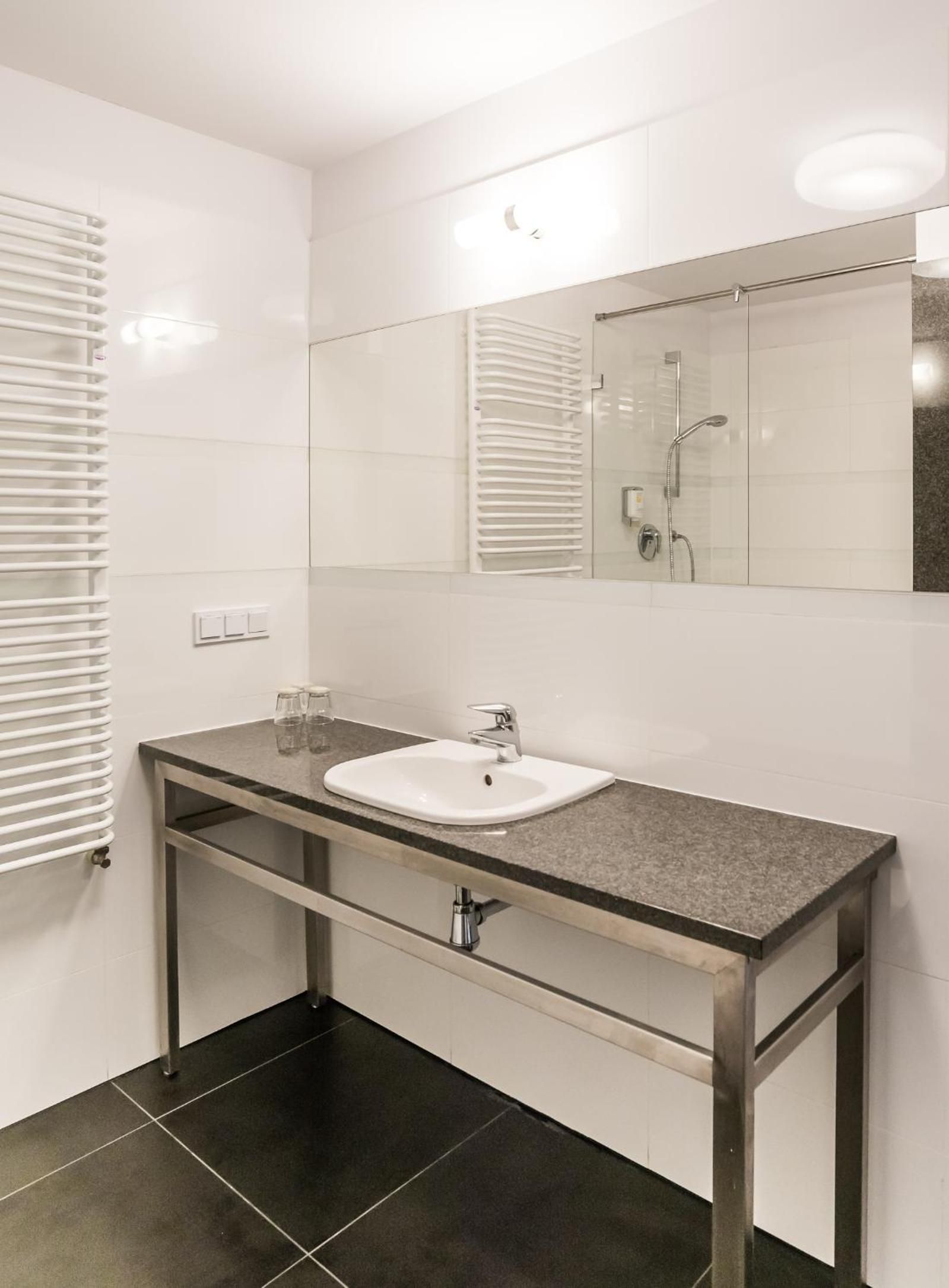 A modern bathroom with a white sink, a mirror, and a shower.