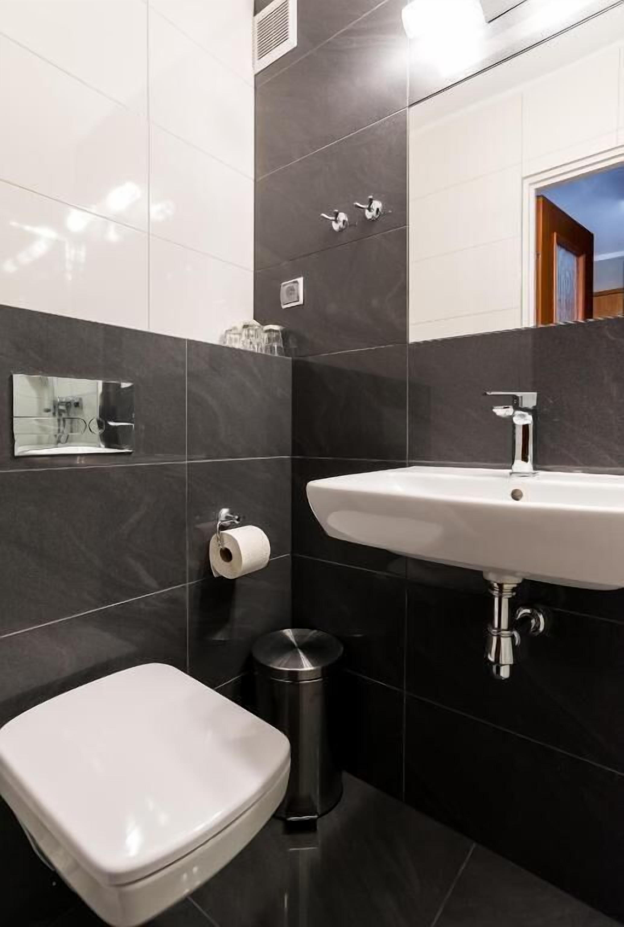 A modern bathroom with a white toilet, a sink, and a trash bin.