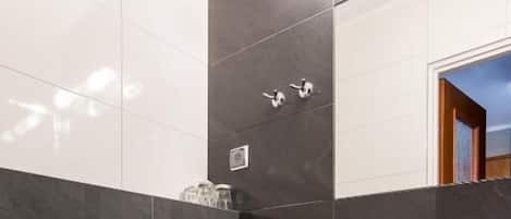 A modern bathroom with a white toilet, a sink, and a trash bin.