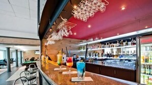 A bar area with a counter, bar stools, and a variety of drinks.