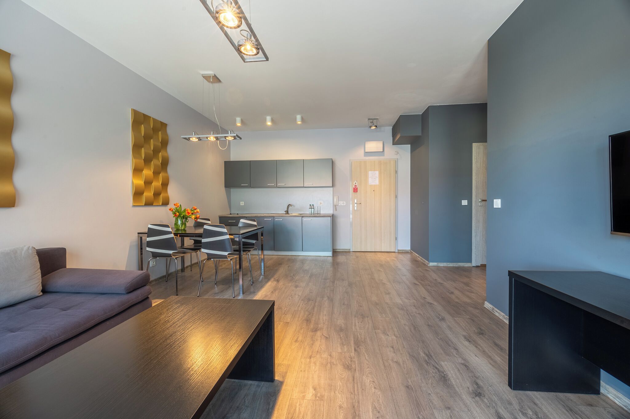 Een moderne woonkamer met een bank, eettafel en een keuken op de achtergrond.