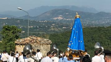 A group of people in white shirts and black hats walking towards a statue with a blue cloth and a golden crown.