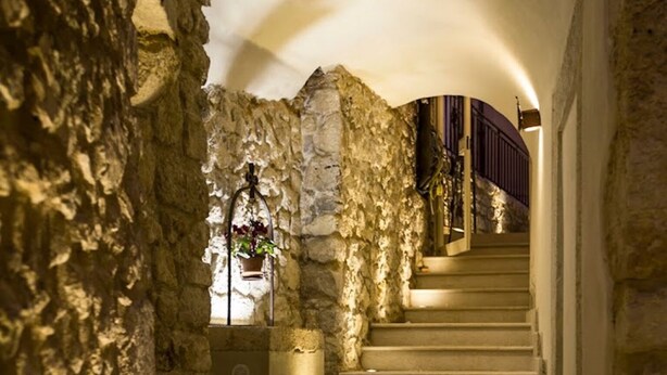 A stone staircase in a building with a warm light source at the top. - Sotto Le Stelle (Picinisco)