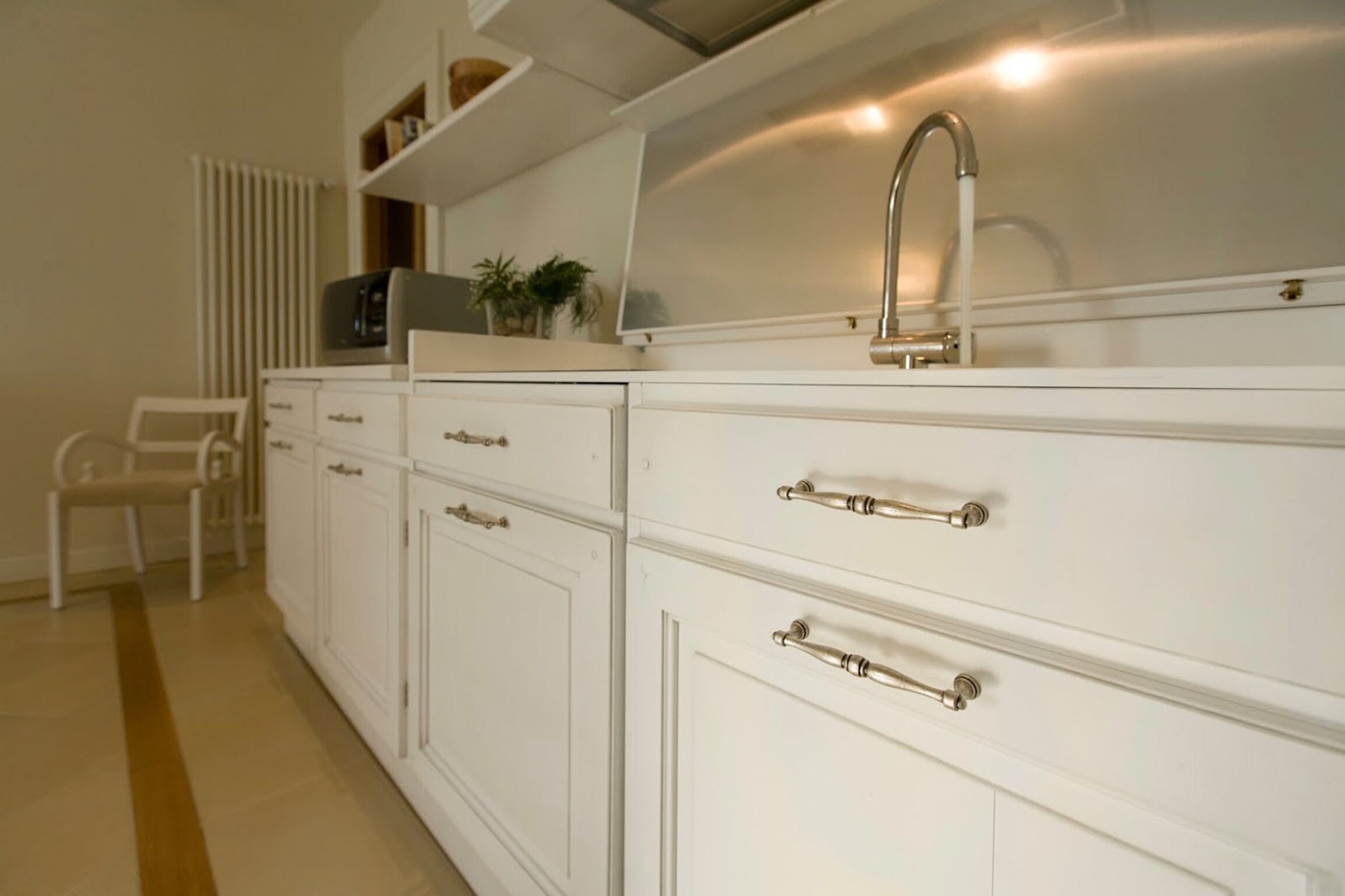 Una cocina con armarios blancos, un grifo de acero inoxidable y un microondas en la encimera.