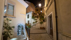 A narrow cobblestone alleyway with buildings on either side, a wrought iron gate, and a street lamp. - Sotto Le Stelle (Picinisco)