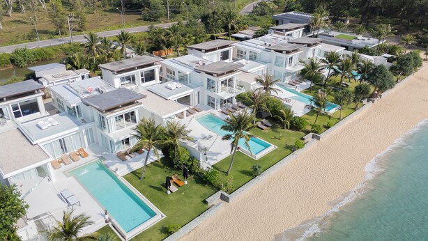Un complexe hôtelier moderne doté de plusieurs piscines, d’une plage et d’une végétation luxuriante.