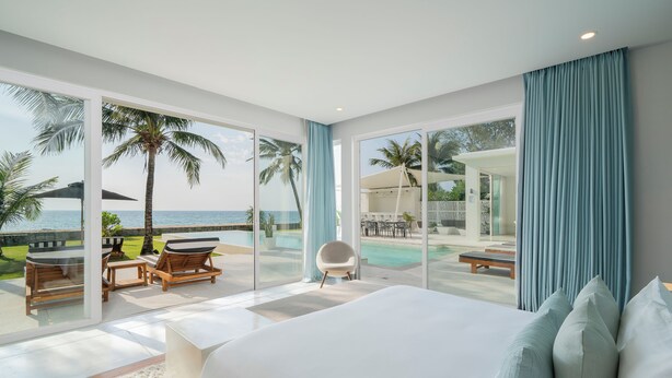 A bedroom with a large bed, a view of the ocean, a pool area, and a dining area with outdoor seating. - Coastal Escape Natai Beach (Takua Thung)