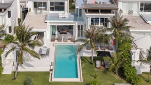 A modern house with a swimming pool, outdoor seating, and palm trees. - Coastal Escape Natai Beach (Takua Thung)
