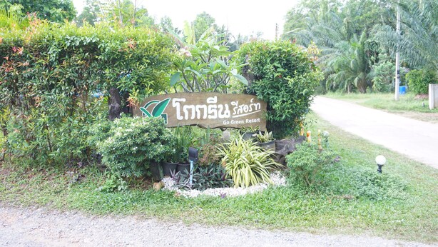 A sign for Go Green Resort surrounded by lush greenery and potted plants. - Go Green Resort (Chumphon)