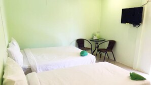 A hotel room with two beds, a small table, two chairs, and a TV mounted on the wall. - Go Green Resort (Chumphon)