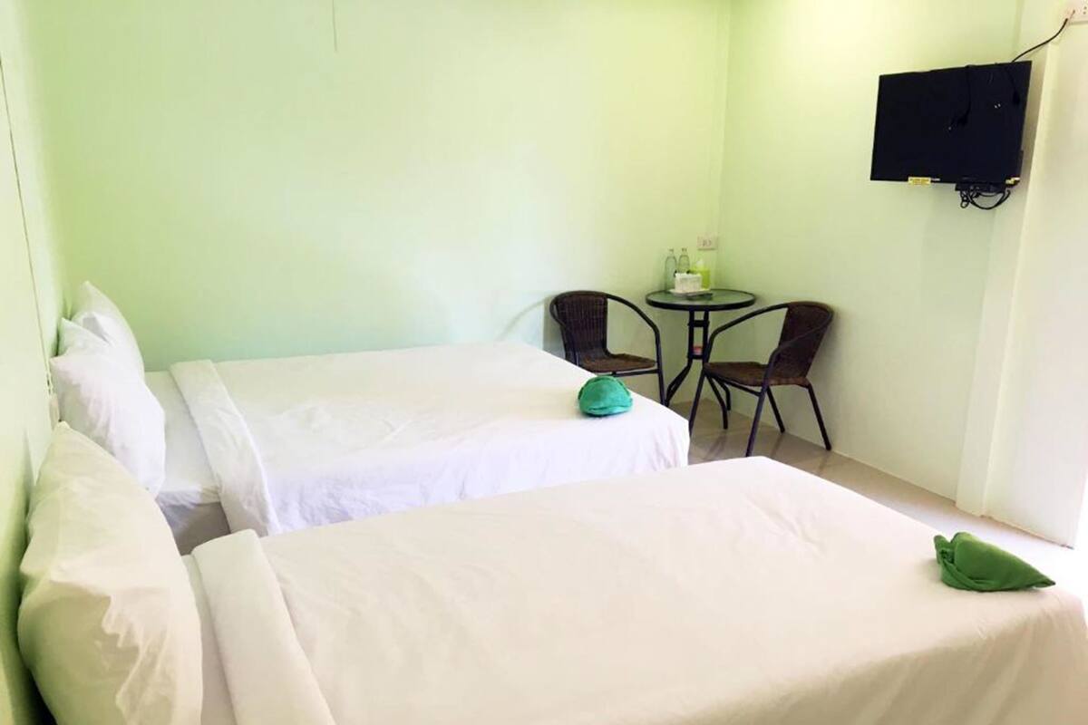 A hotel room with two beds, a small table, two chairs, and a TV mounted on the wall.