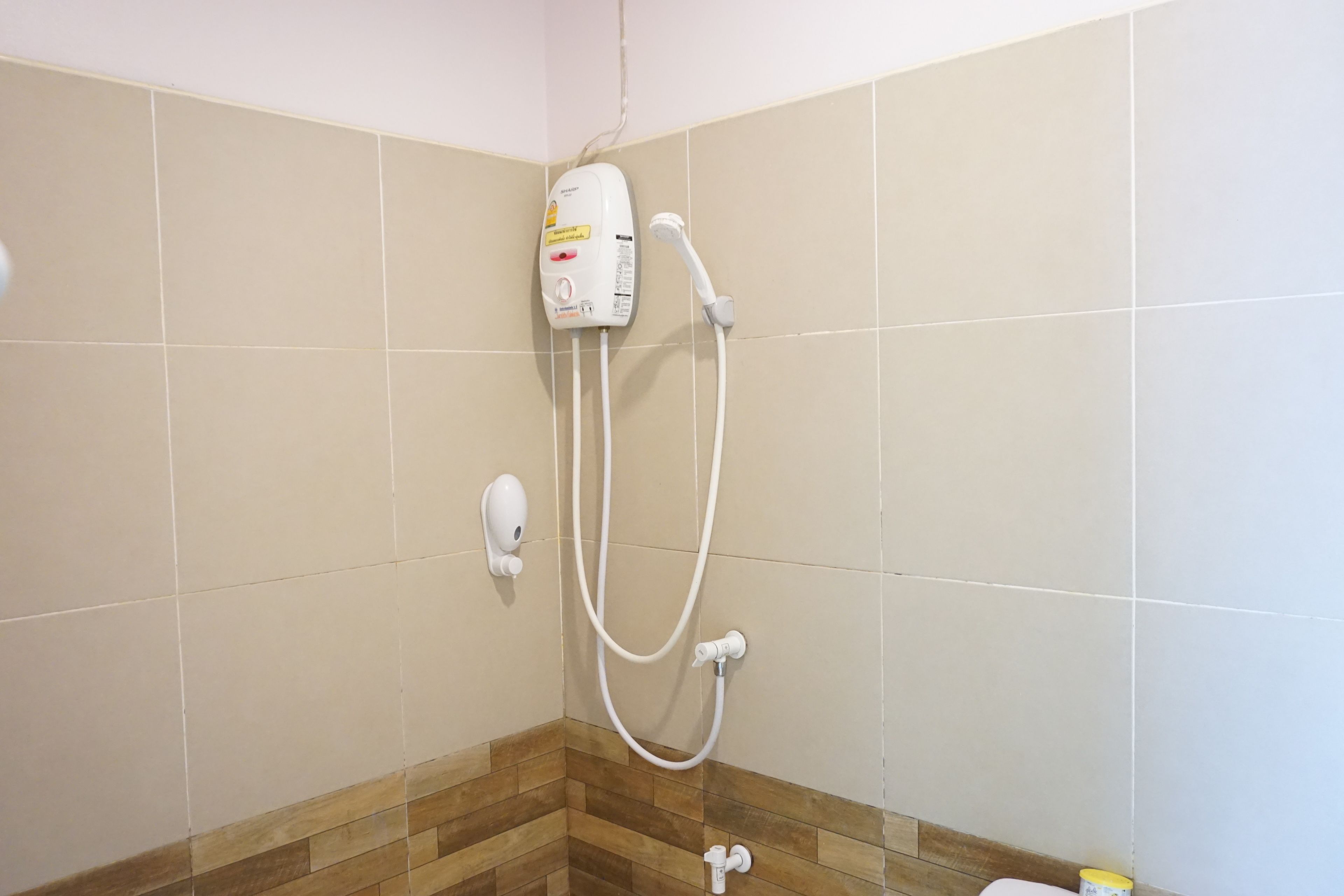 Une salle de bain équipée d’une douche, d’un distributeur de savon et de toilettes.