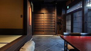 Um interior em estilo japonês tradicional, com uma porta deslizante, soalho de pedra e uma mesa vermelha.