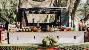 A food stall with a variety of beverages and snacks, surrounded by trees.