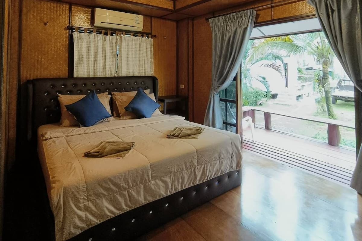 Un dormitorio con una cama grande, un ventilador de techo y una ventana con cortinas.
