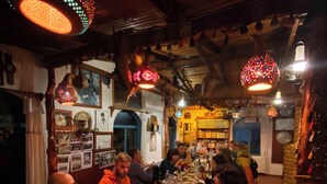 Een groep mensen dineert aan een houten tafel in een gezellig verlicht restaurant met decoratieve hanglampen.