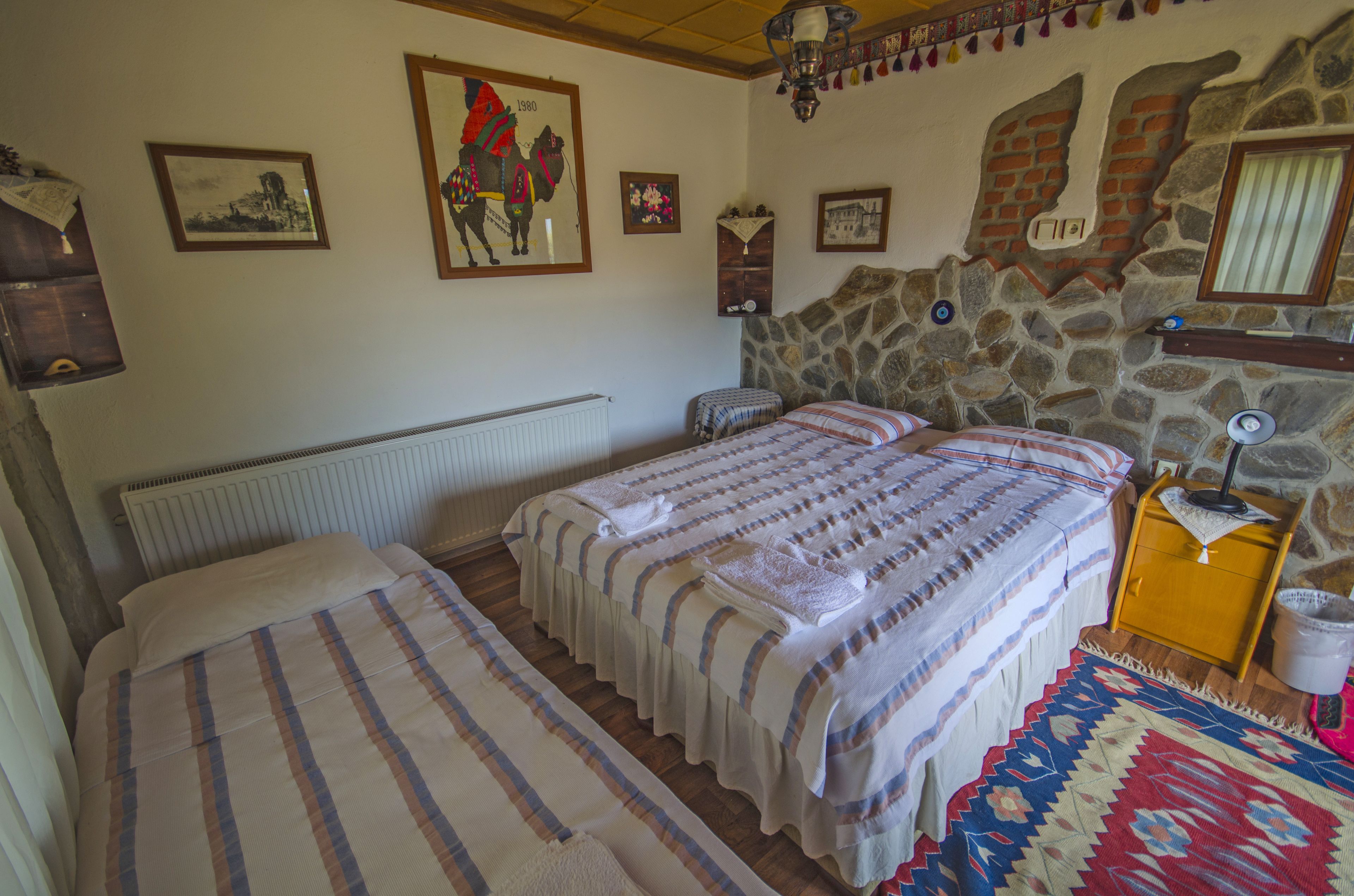 Un dormitorio con dos camas, una pared de piedra y una decoración rústica.