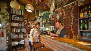 Een bar met een bakstenen muur, houten planken met boeken en een behanget muur.