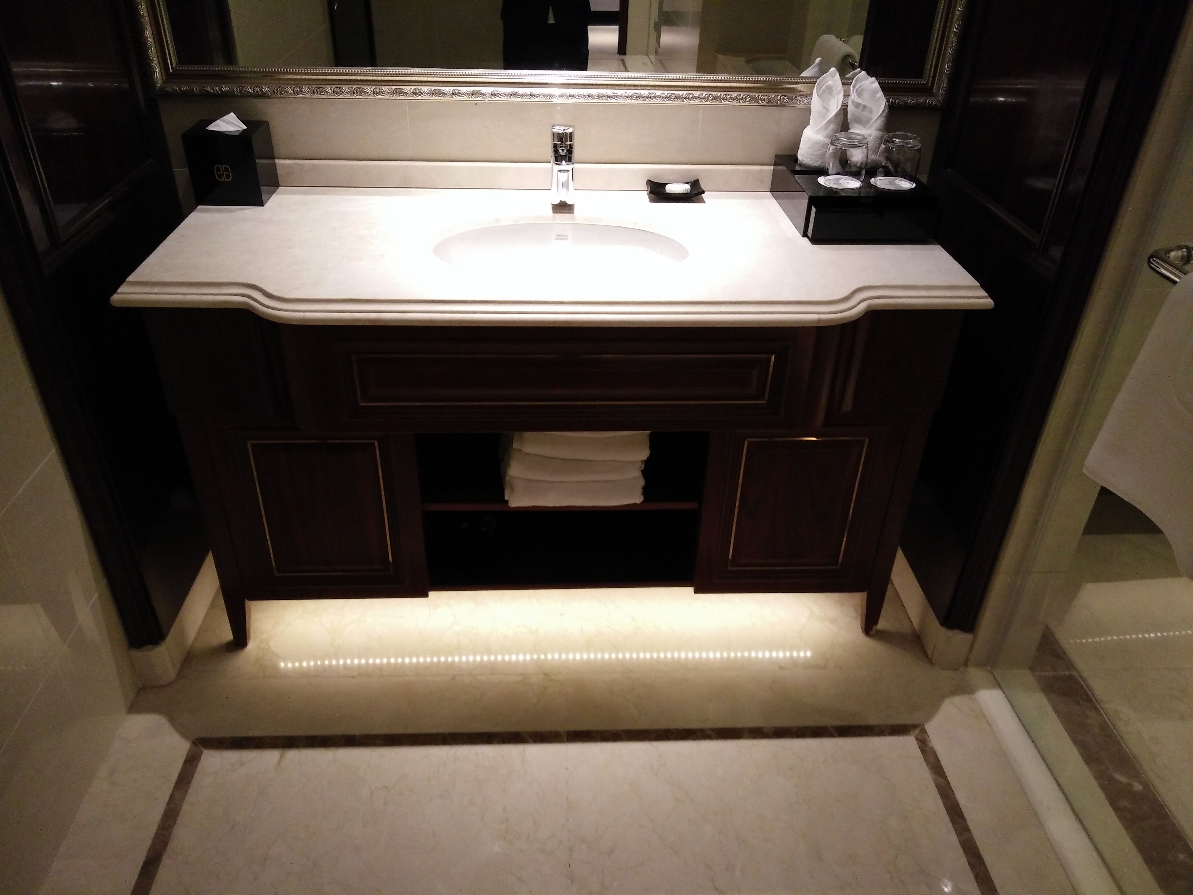 Un baño con un espejo grande, un lavabo y un perchero para toallas.